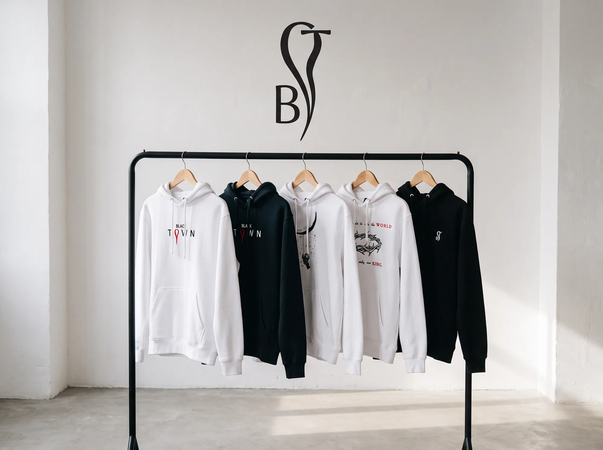 Pět mikin Blacktown na stojanu v bílém studiu, na zdi monogram B