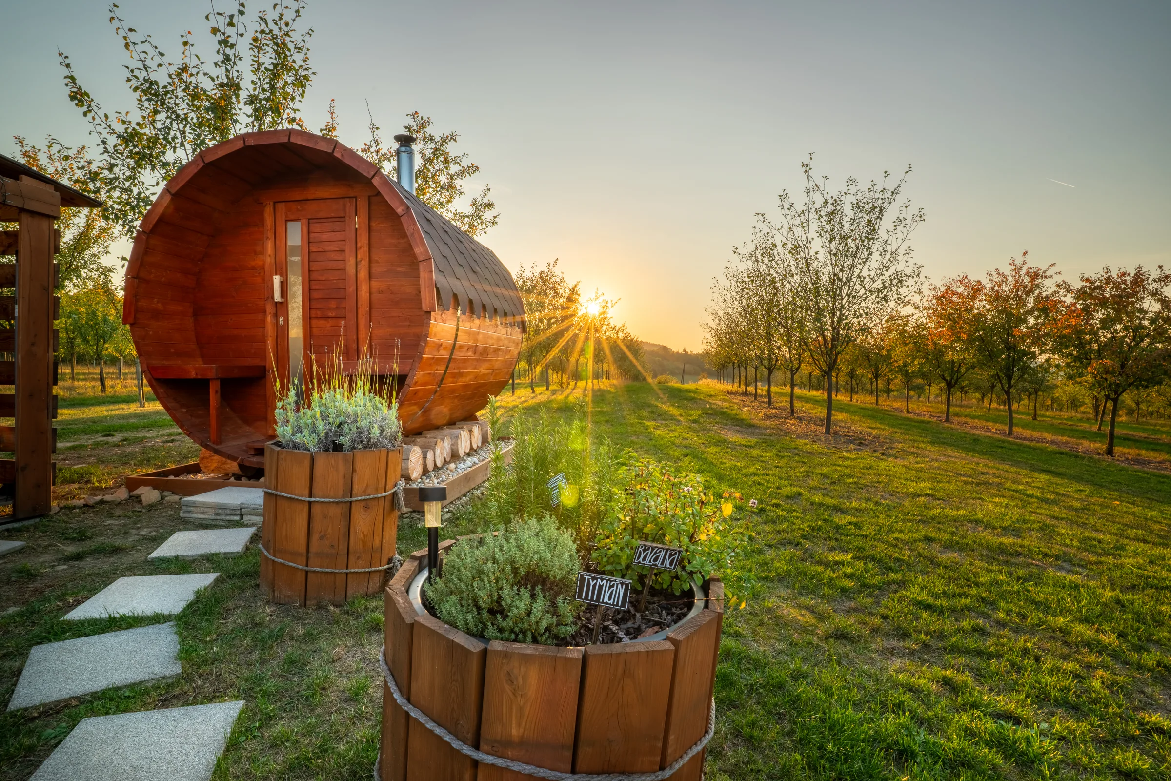 Tiny house Glampidol se saunou v trnkovém sadu při západu slunce