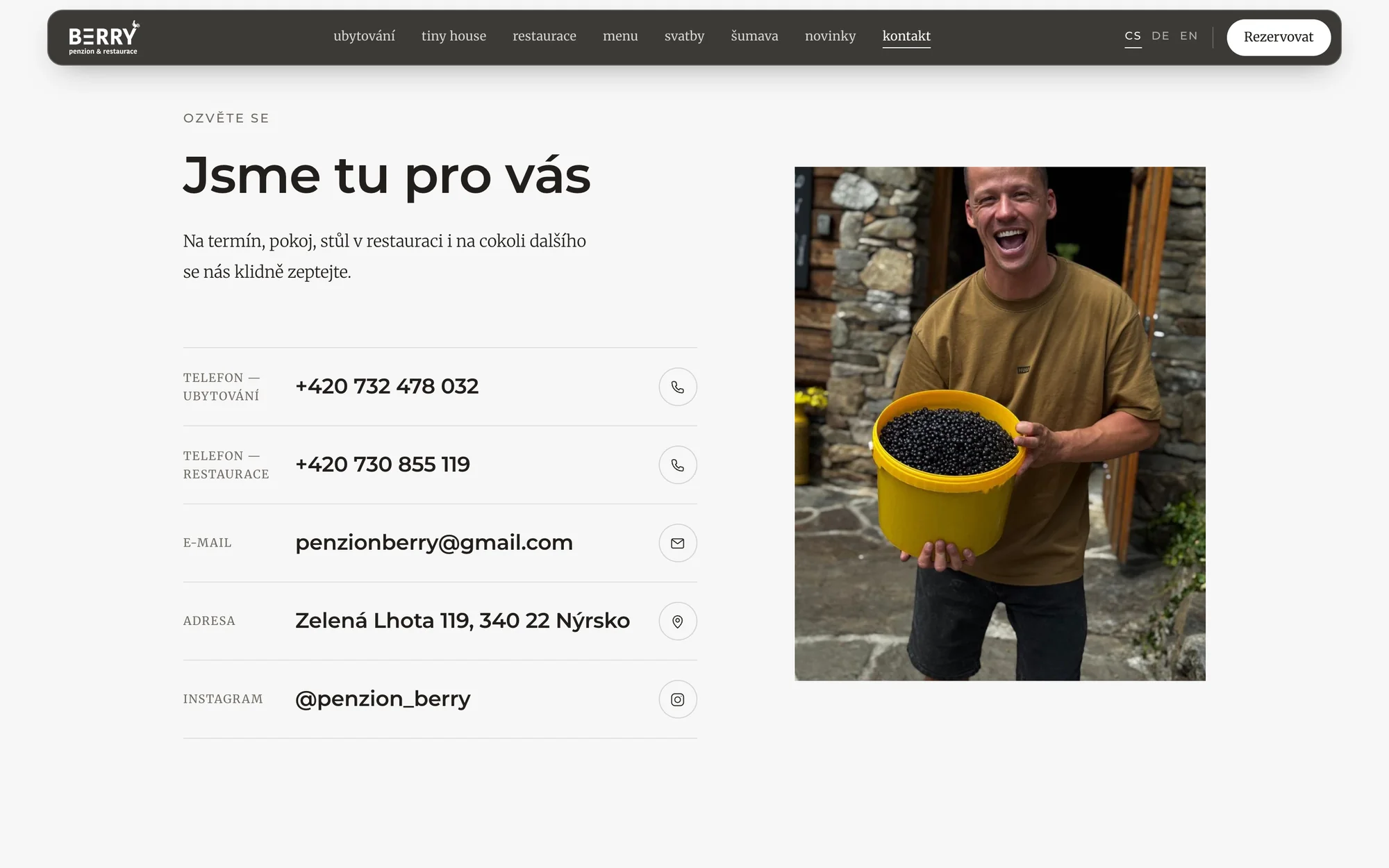 Stránka Kontakt: telefony na ubytování a restauraci, e-mail, adresa a Instagram vedle fotky muže s kbelíkem borůvek
